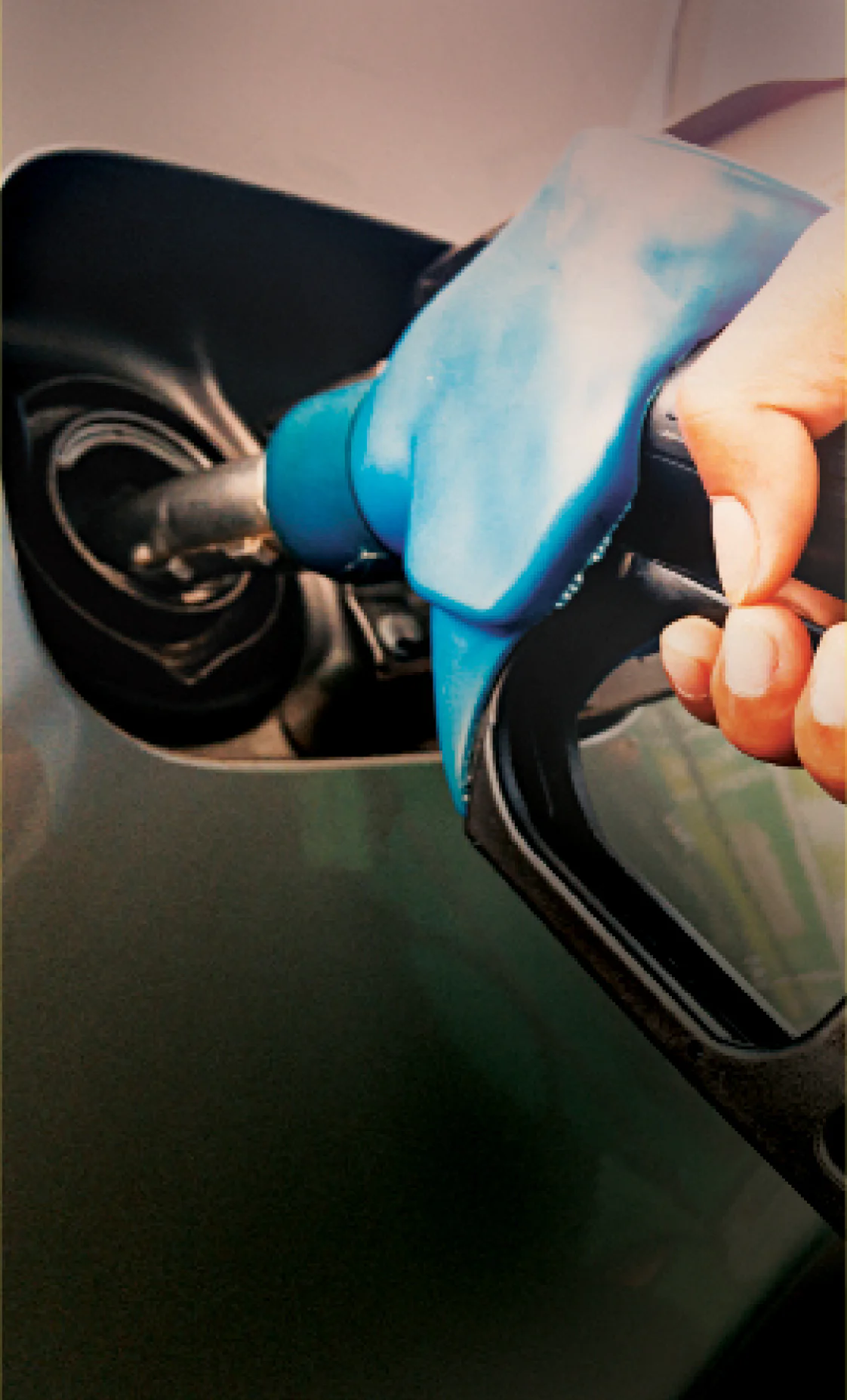 Pessoa abastecendo um tanque de gasolina com um bico azul, em um posto de combustíveis.